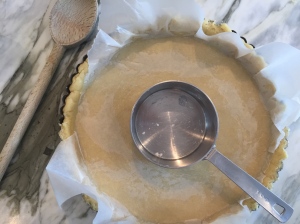 Using your fingers and the bottom of a flat bottomed measuring cup, press the dough evenly to cover bottom and sides of tart pan.