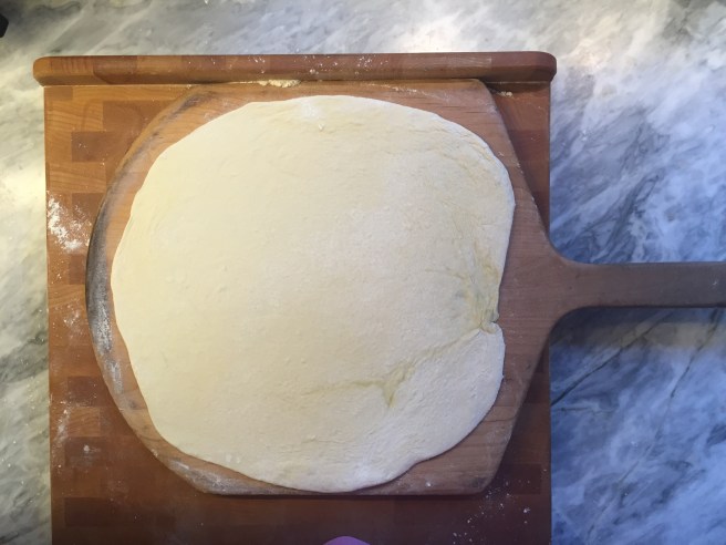 After rolling, the dough is transferred to a well floured pizza peel.