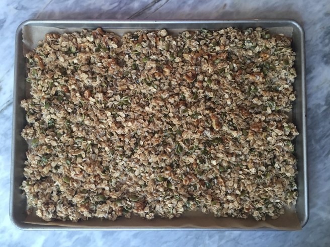 Wet granola ingredients on a cookie sheet, ready for the oven.