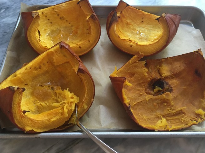 Roasted pumpkin being scooped out.