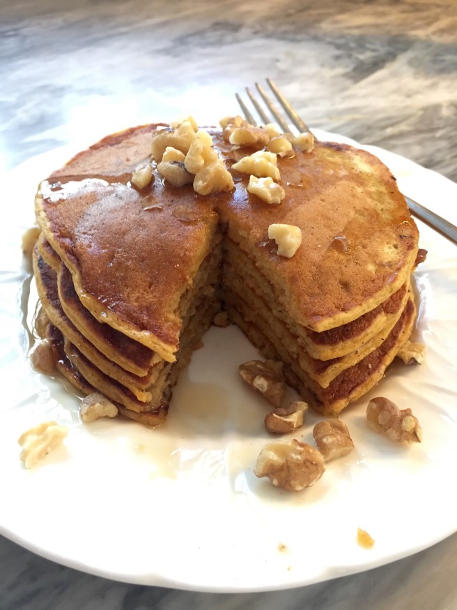 Pumpkin pancakes served with warm maple syrup and toasted walnuts.