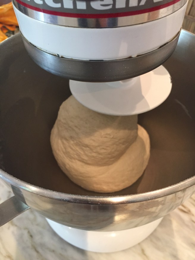 Using a dough hook attachment to knead the dough.