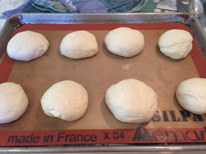 Raw pretzel buns on silicone lined sheet pan.