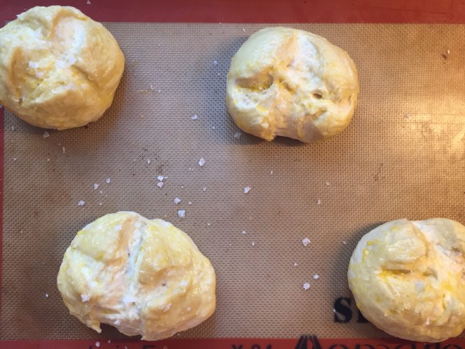 Egg washed buns sprinkled with flaked sea salt.