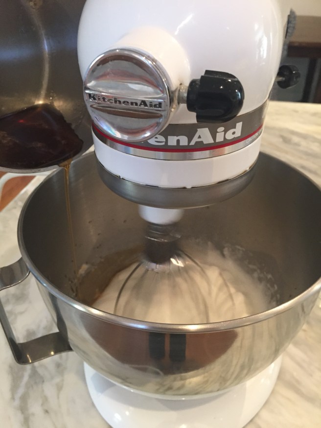 Pouring hot syrup into beaten egg whites.