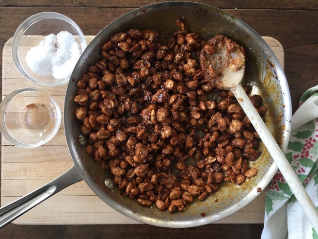 Adding chili, cinnamon, and salt to candied peanuts.