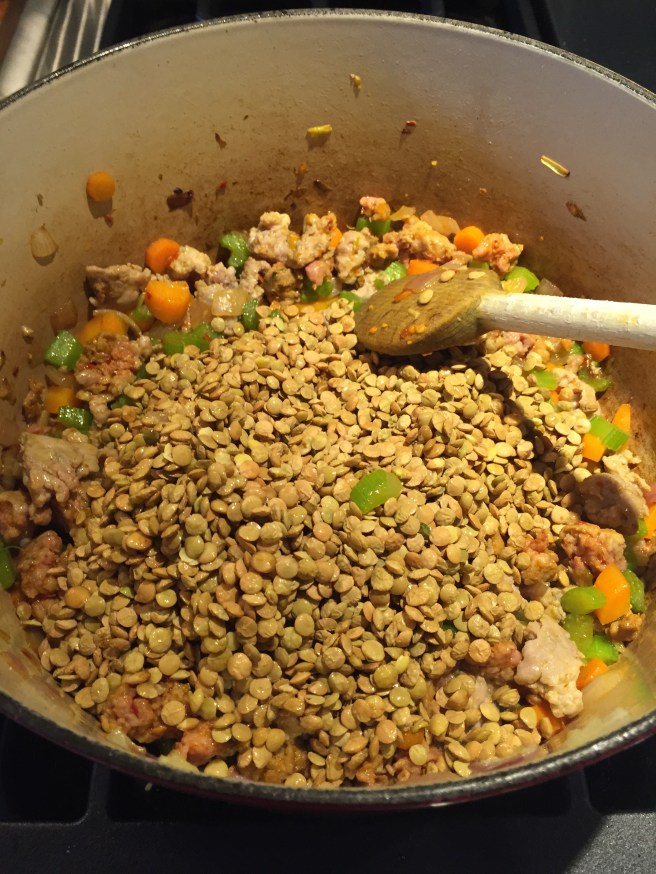 Adding green lentils to sausage and vegetable mixture.