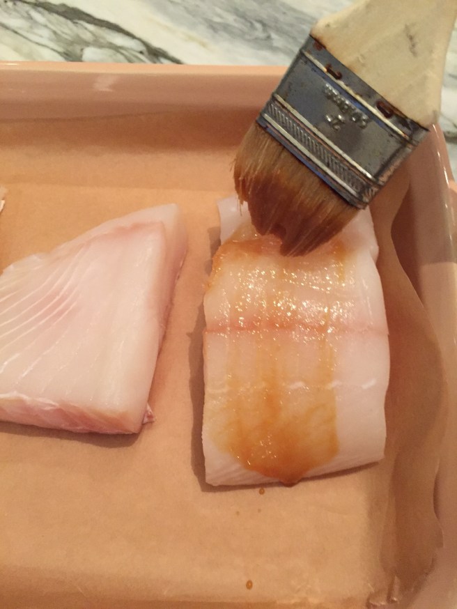 A pastry brush glazes the top and sides of fish fillet.