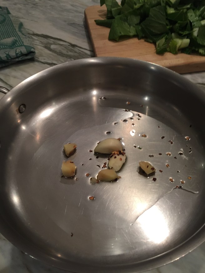 Garlic, ginger, and red pepper flakes warming in a skillet.