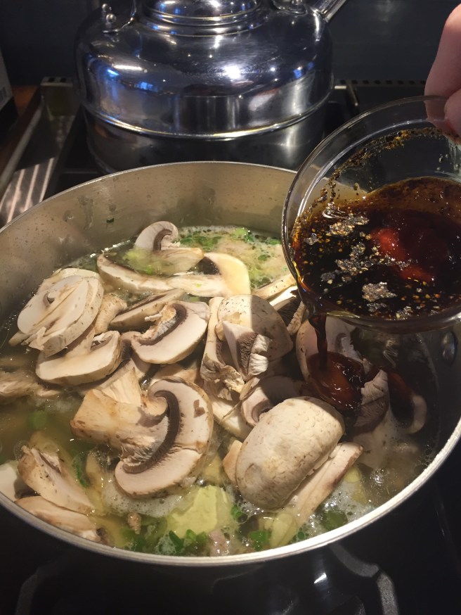 Adding sugar, vinegar, soy sauce, black pepper, sesame oil, and Sriracha to soup