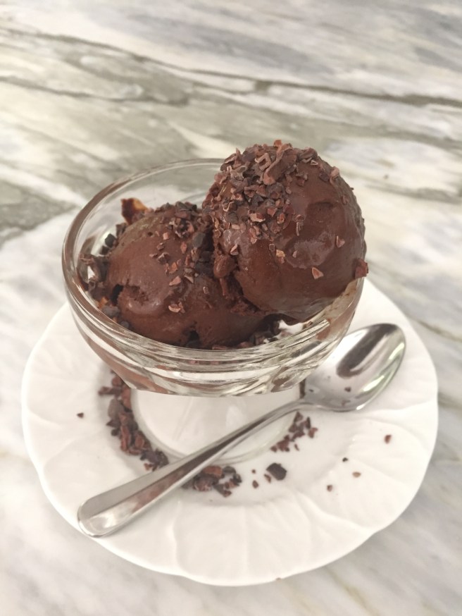 Bittersweet Chocolate and Honey Sorbet sprinkled with cocoa nibs and served in a glass dish.